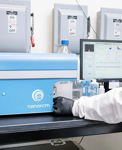 A gloved hand loading a sample on the NanoFCM nanoparticle analyzer