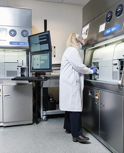 A staff member at a FACSAria Fusion cell sorter inside its biosafety enclosure