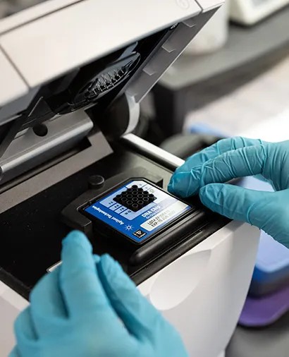Gloved hands placing a chip into an Agilent Bioanalyzer