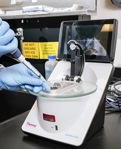 A pipette loading a drop of sample onto a NanoDrop One